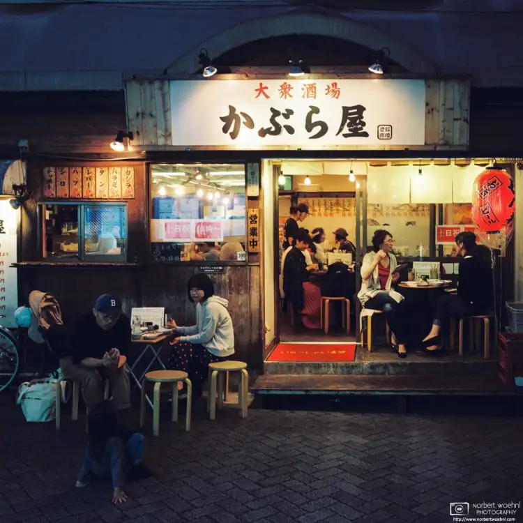 Evening life at an Izakaya (Japanese pub) in the Asagaya area of Tokyo, Japan. People are casually chatting and playing with their kids.
