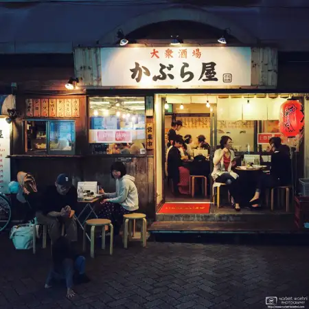 Evening life at an Izakaya (Japanese pub) in the Asagaya area of Tokyo, Japan. People are casually chatting and playing with their kids.