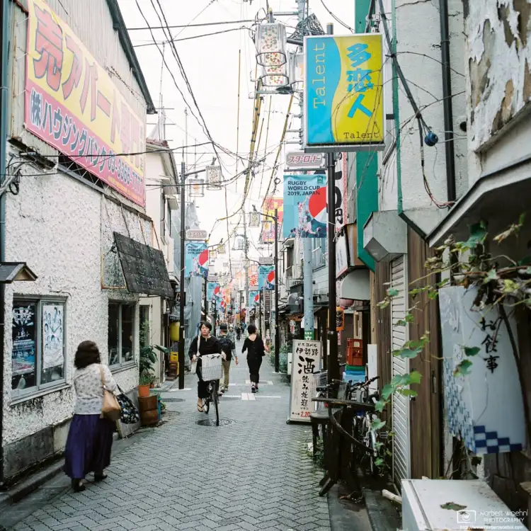 Pedestrian and bicycle traffic along Star Road, a pub-lined alley in Asagaya, Tokyo, Japan.