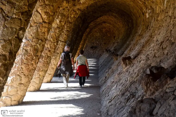 Visitors are seen walking down a colonnaded pathway at Antoni Gaudí’s Parc Güell in Barcelona, Spain.