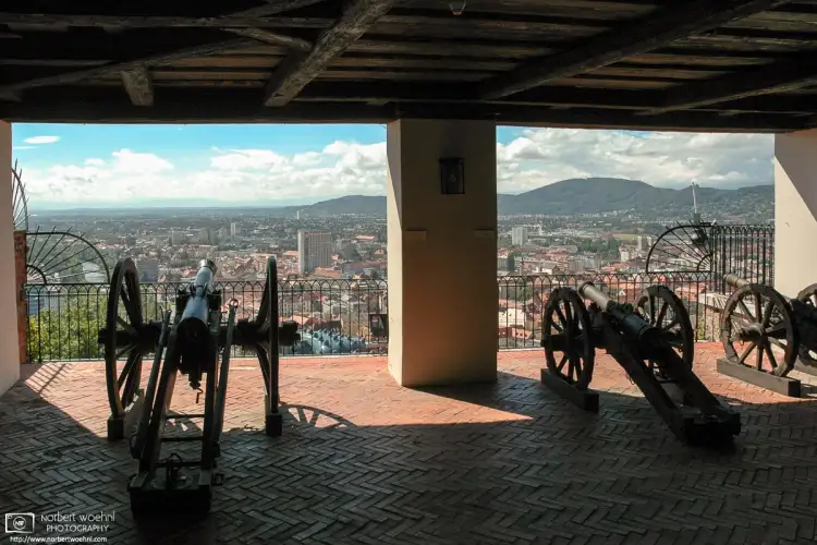 Cannons at the Schlossberg Bastion in Graz, Austria, opening up a view towards the historic city center which is a UNESCO World Heritage site.