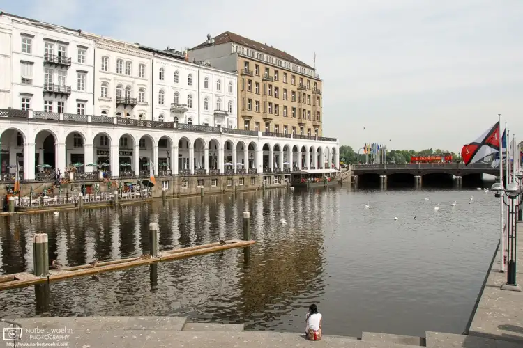 In Hamburg, Germany, a woman is enjoying this splendid view across the Alsterfleet, with the historic Alsterarkaden shopping arcade visible at the left.