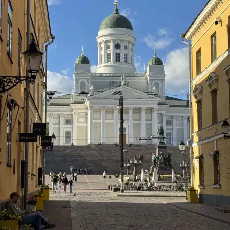 Evening view of Helsinki Cathedral and Senate Square from Sofiankatu, a cobblestone street lined with old buildings.