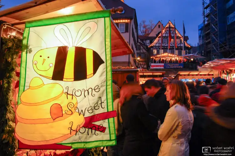 At the Christmas Market in the historic town of Herrenberg in southwestern Germany, people are looking at a stand selling honey and beewax products.