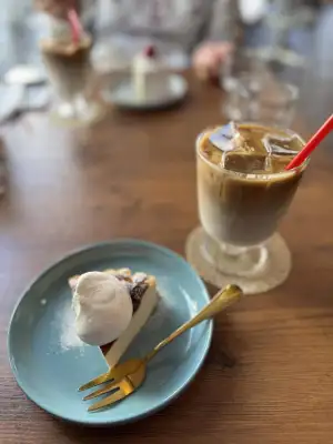An iced caffe latte and a slice of Basque cheesecake with a topping of whipped cream.