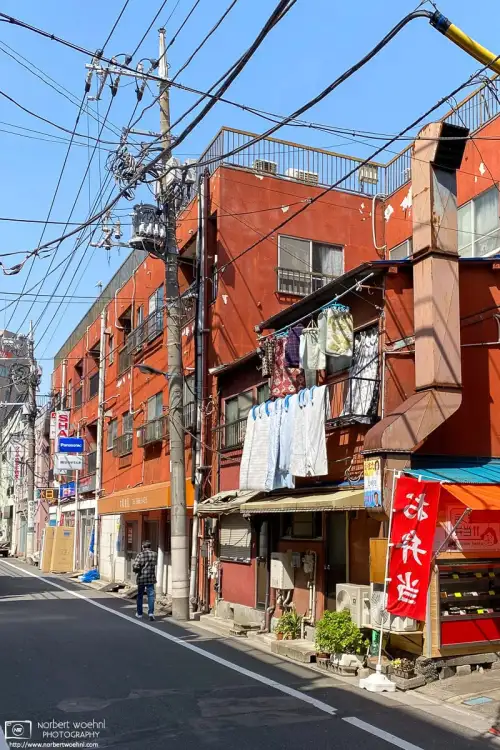 Colorful scene on a backstreet in the Itabashi Ward of Tokyo, Japan. In front a bento shop and laundry day, further back some boxes outside an electronics store.