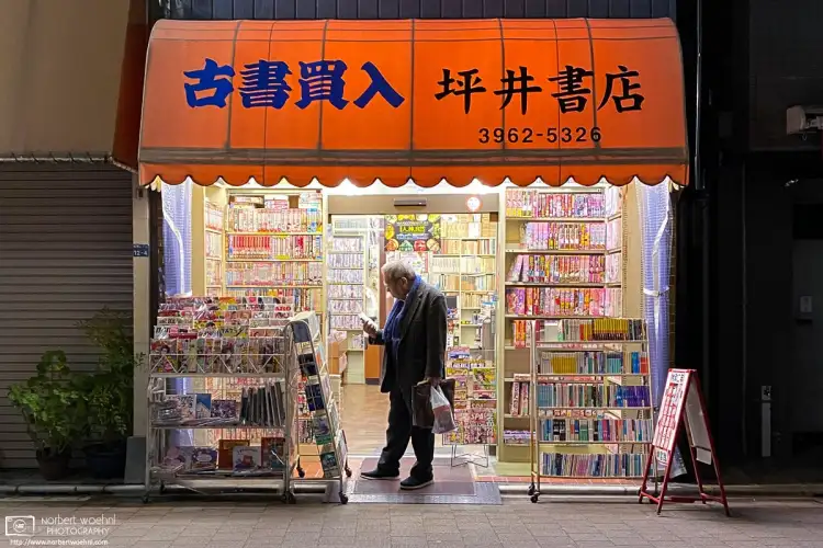 A customer is weighing a purchase at a small neighborhood bookstore in the Itabashi Ward of Tokyo, Japan.