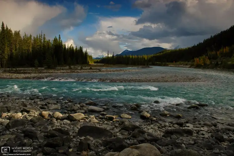 The last beams of sunlight are hitting rocks along the Athabasca River in Jasper National Park, Alberta, Canada.