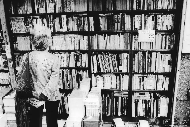 A woman scanning a shelf of used books at Jimbōchō, the Tokyo neighborhood known for its high concentration of used-book stores and publishing houses.