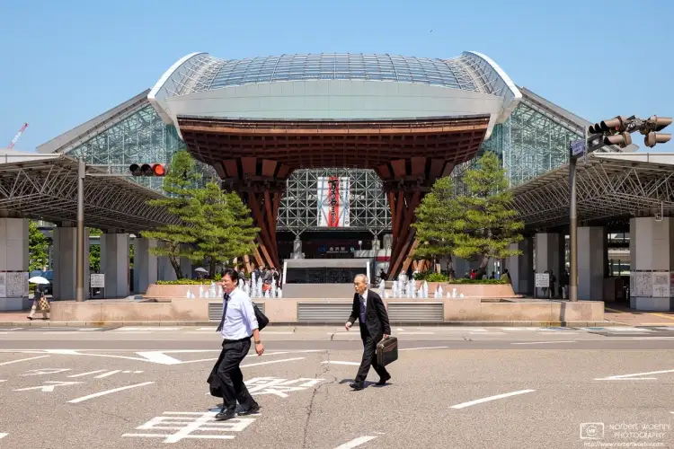 Two salarymen are seen traversing the crossing in front of Kanazawa Station in Ishikawa Prefecture, Japan.