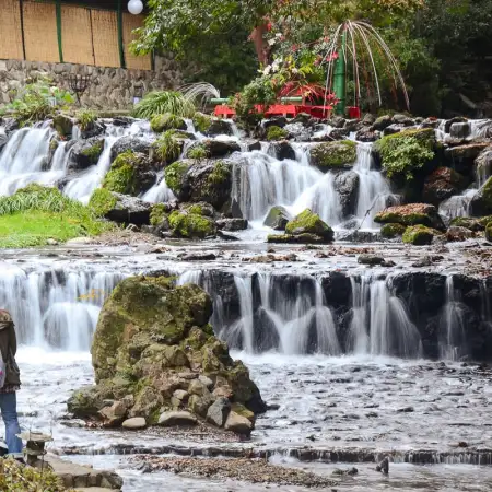 A young couple is seen photographing the cascades of Kibune River in Kyoto, Japan.