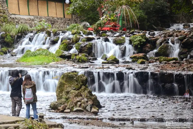 A young couple is seen photographing the cascades of Kibune River in Kyoto, Japan.