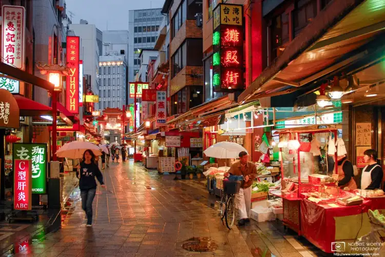 Colorful neon signs, restaurants and food stalls on a rainy evening in the Chinatown area of Kobe, Japan.