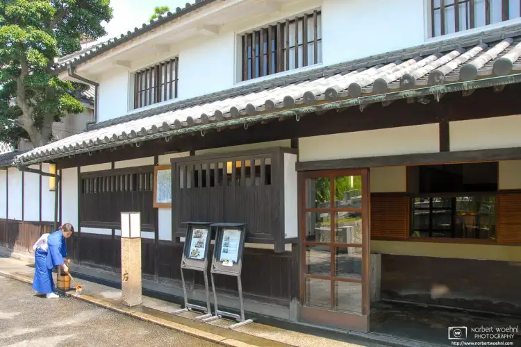Staff is watering the pavement outside a Ryokan (traditional Japanese inn) in the Bikan historical district of Kurashiki, Japan.