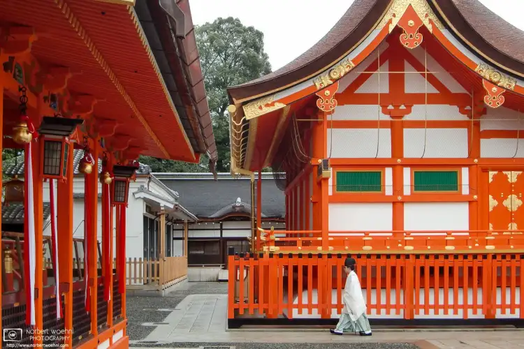 A priest walking between the buildings in the lower area of Fushimi Inari Taisha in Kyoto, Japan.