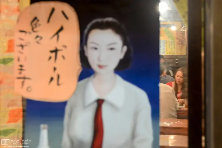 View into an Izakaya (Japanese-style pub) through a Showa-period highball advertisement as seen in Kyoto, Japan.