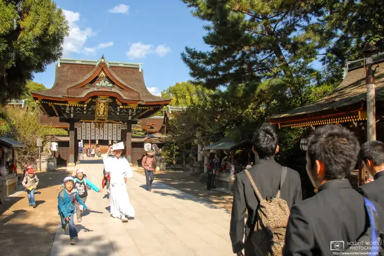 Students of different ages are visiting the grounds of Kitano Tenmangū Shrine in Kyoto, Japan.