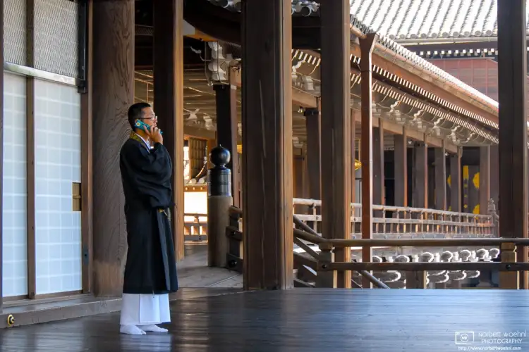 A priest answering his mobile phone at Nishi-Honganji Temple in Kyoto, Japan.