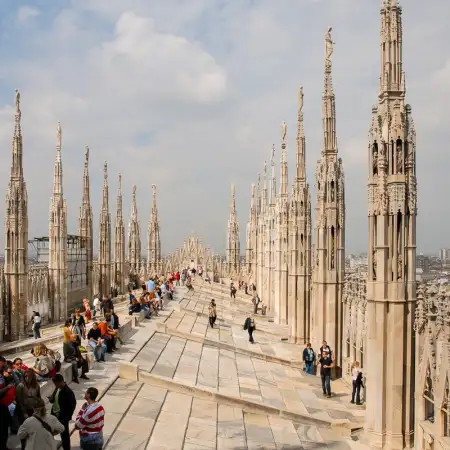 Tourists taking in the incredible views from the rooftop of Duomo di Milano, the cathedral church of Milan, Italy.