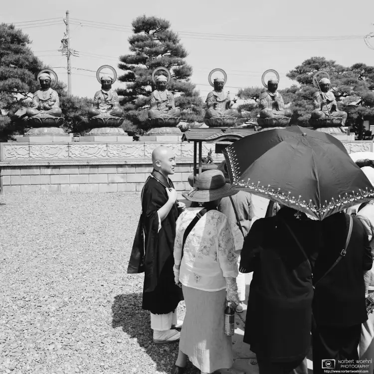 In front of Rokujizō (Six Jizo) Statues, a priest is giving a guided tour of Zenkōji Temple in Nagano, Japan.