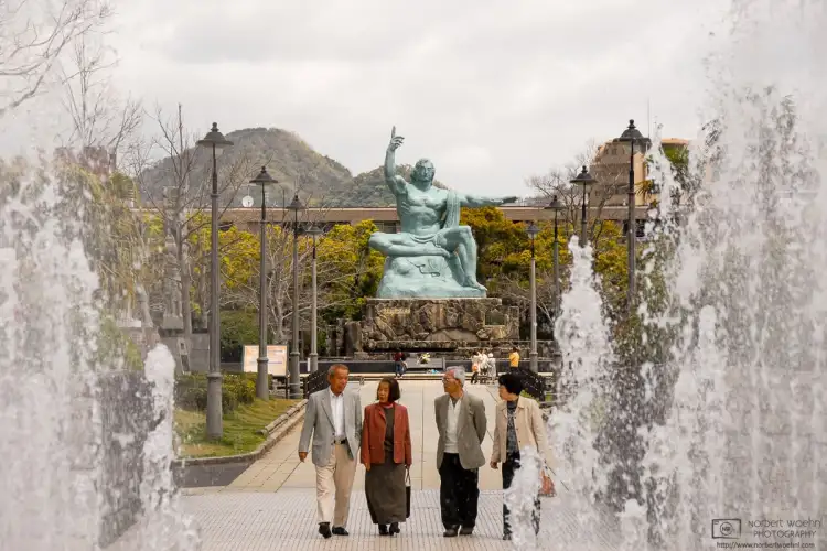 Framed by the water jets of a fountain at Nagasaki Peace Park in Japan, four elderly people are seen having a pensive talk.