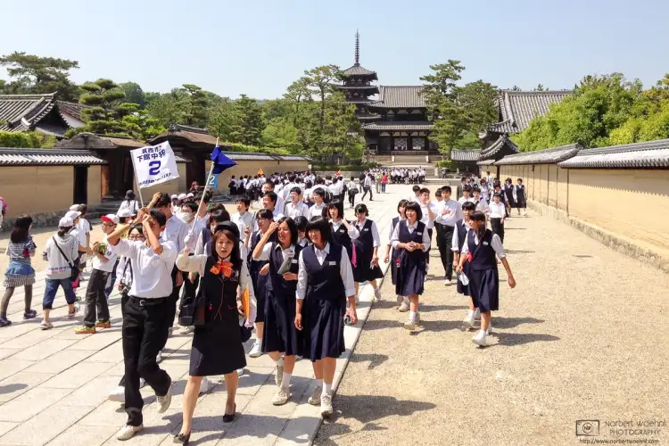 Students are taking a guided tour outside Hōryūji Temple in Nara, Japan.