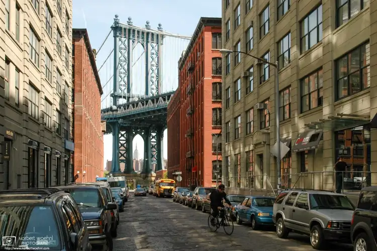 Taken in the DUMBO area of Brooklyn, NY, this photo looks north along Washington Street towards Manhattan Bridge and the distant silhouette of the Empire State Building.