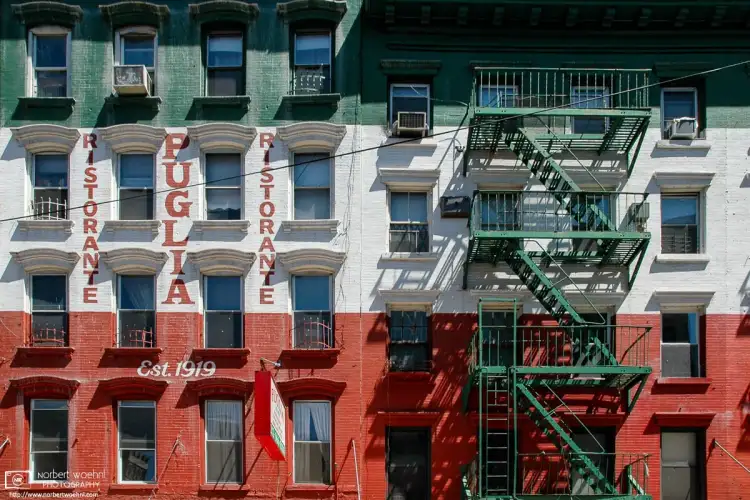 In Little Italy, New York City, a building is painted in the colors of the Italian flag, with even the fire escape stairs matching the green color.