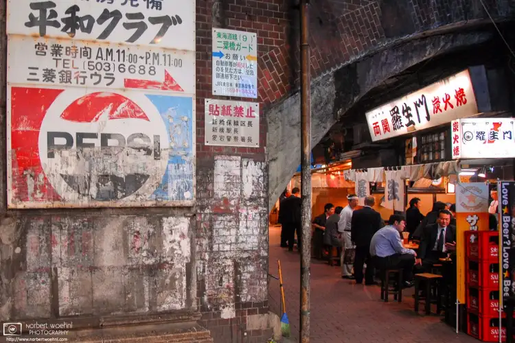Under the tracks of Shimbashi Station in Tokyo, Japan, office workers / salarymen are calling it a day and having a chat over grilled meats and a few beers.