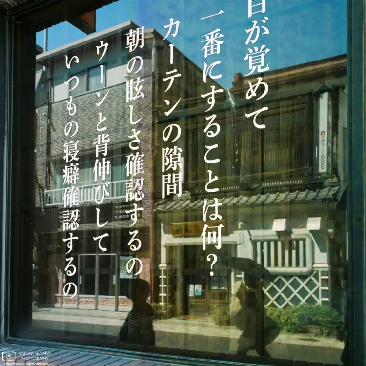 Historic commercial buildings and pedestrian traffic are reflected in a shop window in Ueda, Nagano Prefecture, Japan.