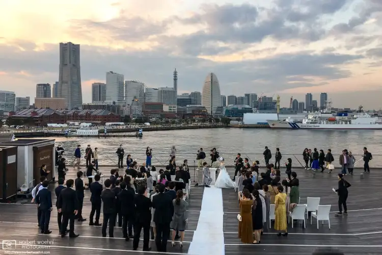 While exploring the docks in the port of Yokohama, I ran into this decisive moment of a wedding ceremony in progress against the grand city skyline in the back.