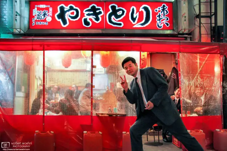 A salaryman posing for my camera (much to the amusement of his companions) outside one of the Yakitori Stalls around Yūrakuchō Station in Tokyo, Japan.