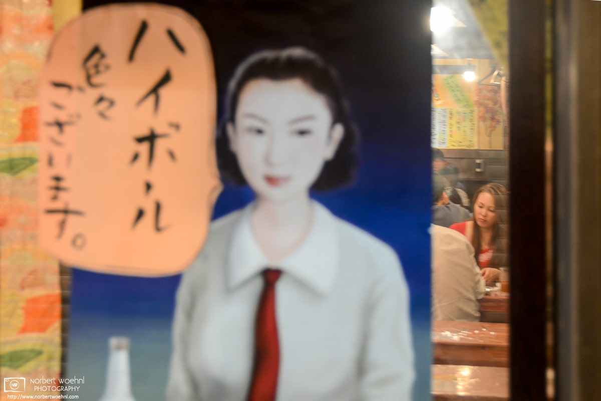 View into an Izakaya (Japanese-style pub) through a Showa-period highball advertisement as seen in Kyoto, Japan.